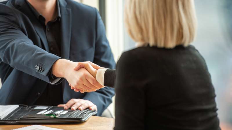 Ein Mandant und ein Business Broker Berater, die sich die Hände schütteln, da sie zum Abschluss gekommen sind.